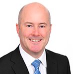 portrait photo of man with black suit jacket, white shirt and blue tie on white background