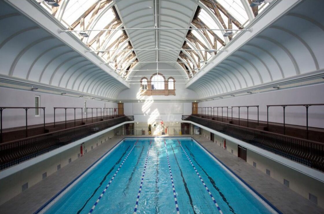 View of length of swimming pool with walk way either side and curved ceiling detail, window to end