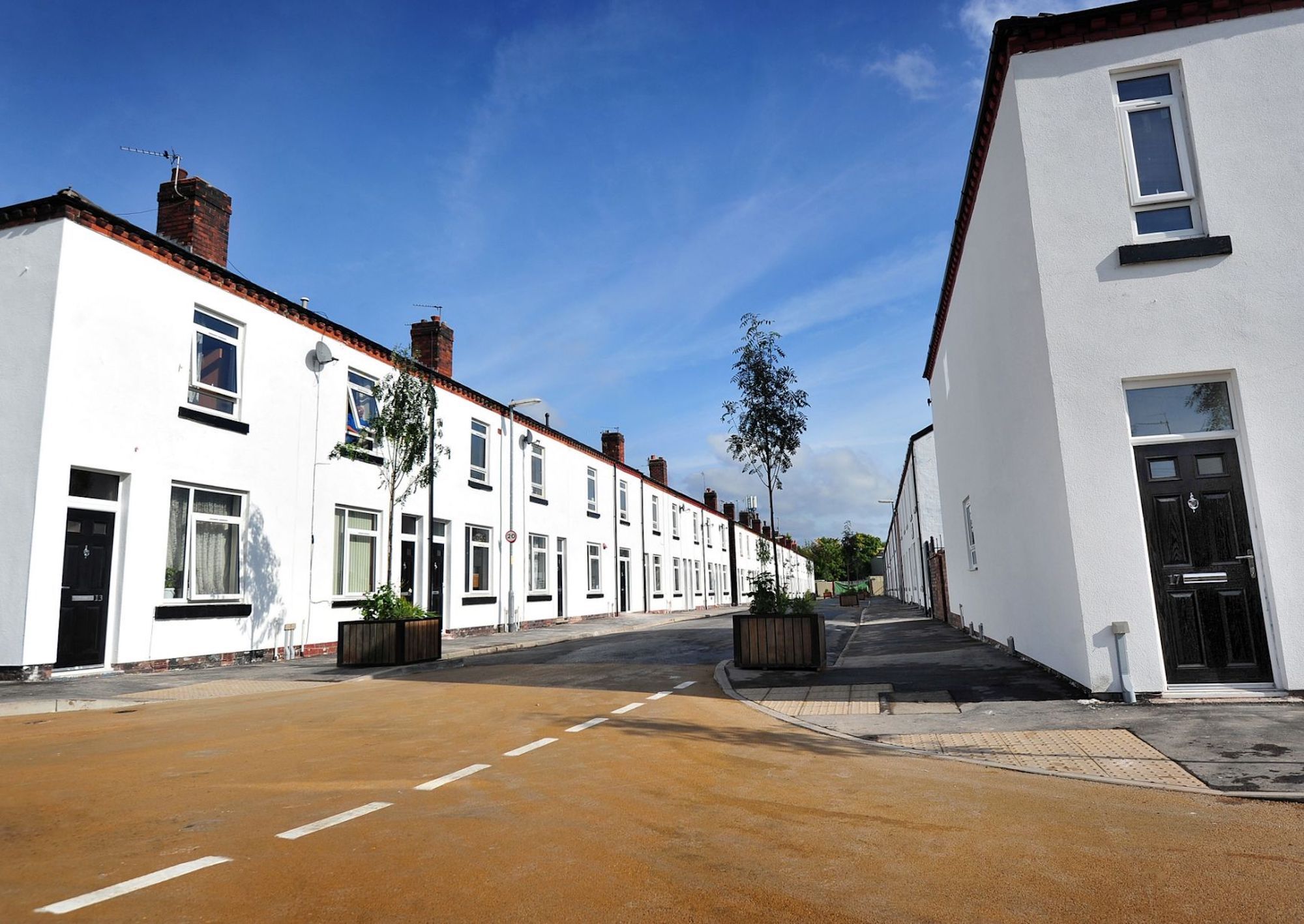 Street with row of houses to either side, rendered finish to all houses and black doors