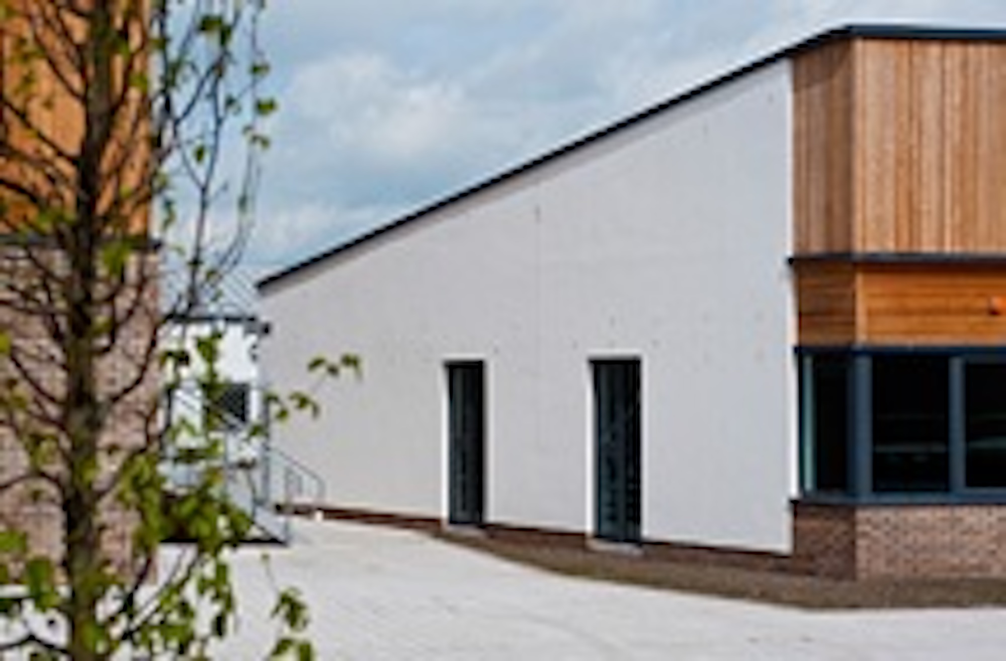 white rendered wall on building with slopped windows to front with wood and brick surround